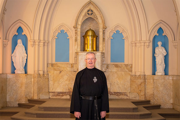 Father Gary Perritt standing and smiling inside church